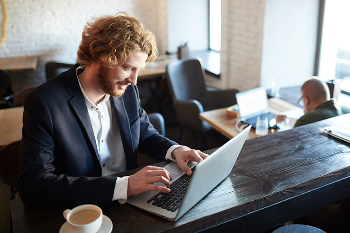 Homem usando laptop e utilizando wi-fi na cafeteria